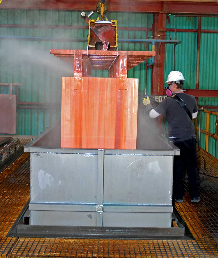 A worker checks as copper sheets are lifted at Bagdad's SXEW plant.